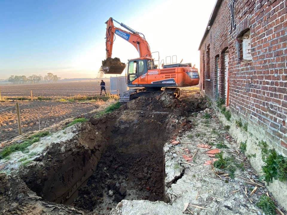 Graafmachine bij een hoeve in ochtendlicht